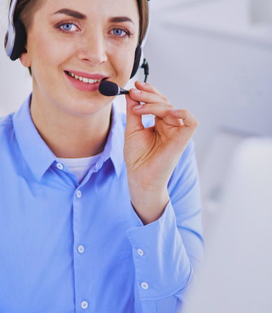 Serious pretty young woman working as support phone operator with headset in officeの写真素材