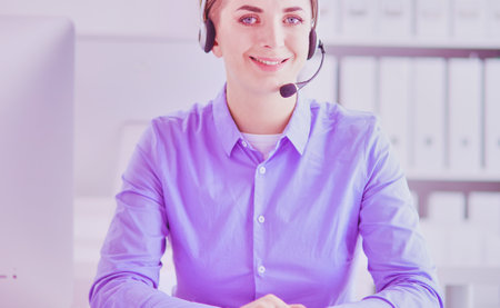 Serious pretty young woman working as support phone operator with headset in officeの写真素材