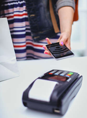Customer is paying with smartphone in shop using NFC technology. NFC technology. Customer is payingの写真素材