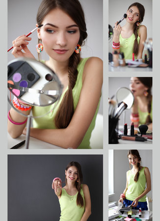 Young beautiful woman making make-up near mirror,sitting at the deskの写真素材