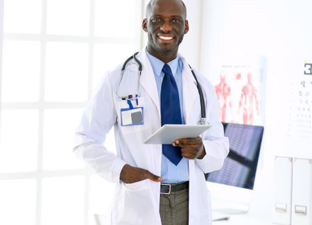 Male black doctor worker with tablet computer standing in hospitalの写真素材