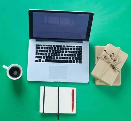 Notebook with gifts and laptop on wooden tableの写真素材