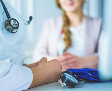 Doctor and patient discussing something while sitting at the table . Medicine and health care conceptの写真素材