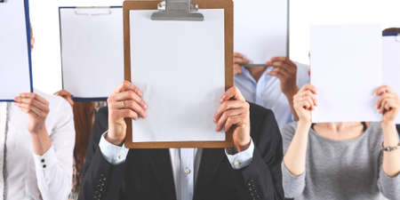 Team of businesspeople holding a folders near face isolated on white backgroundの写真素材