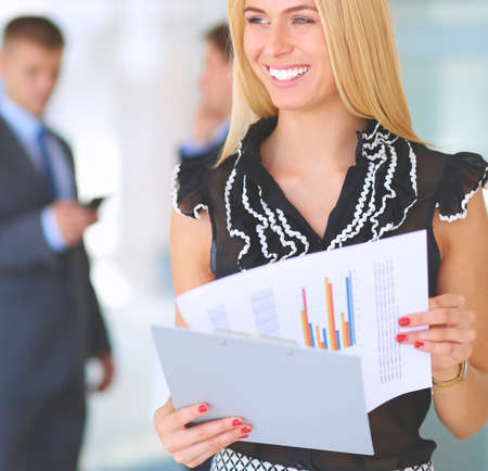 Business woman standing in foreground with a folder in her handsの写真素材