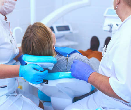 Senior male dentist in dental office talking with female patient and preparing for treatmentの写真素材