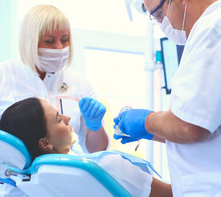 Dentist and his assistant carrying out a thorough examinationの写真素材