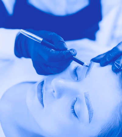 Cosmetologist applying permanent make up on eyebrowsの写真素材