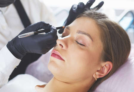 Cosmetologist applying permanent make up on eyebrowsの写真素材