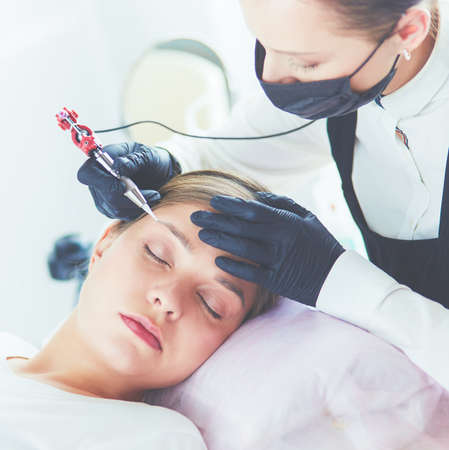 Young woman undergoing procedure of eyebrow permanent makeup in beauty salonの写真素材