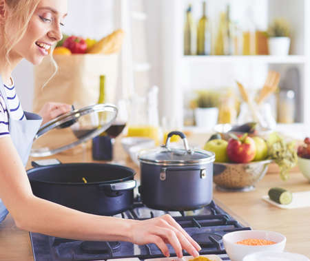 Beautiful young woman cooking in kitchen at homeの写真素材