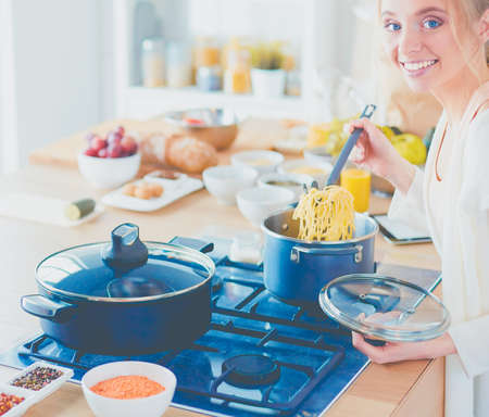 Beautiful young woman cooking in kitchen at homeの写真素材