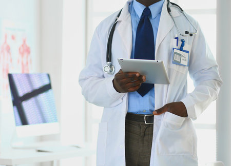 Male black doctor worker with tablet computer standing in hospitalの写真素材