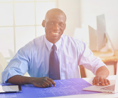 African american architect working with computer and blueprints in officeの写真素材