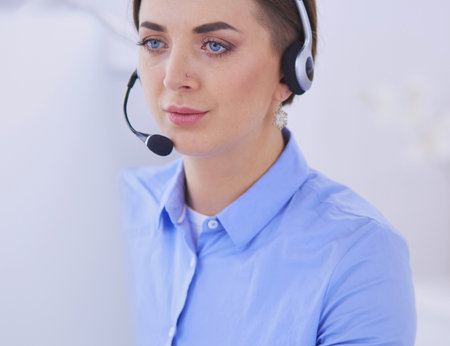 Serious pretty young woman working as support phone operator with headset in officeの写真素材