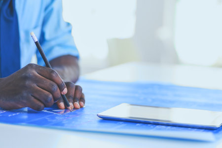 African american architect working with computer and blueprints in officeの写真素材