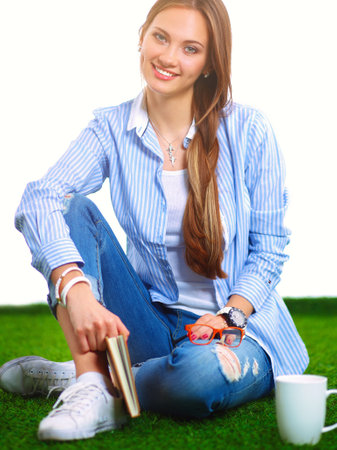 Young woman sitting with book on grassの写真素材