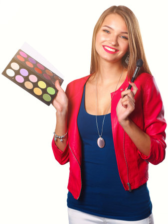 Young beautiful woman holds in one hand and a palette with paint and shadows for makeup, second hand brush for makeupの写真素材