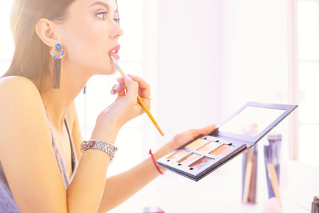 Brunette woman applying make up for a evening date in front of a mirrorの写真素材