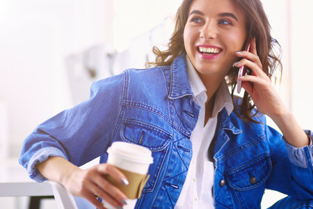 Young businesswoman talking on the phone in coffee shopの写真素材
