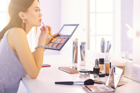 Brunette woman applying make up for a evening date in front of a mirrorの写真素材
