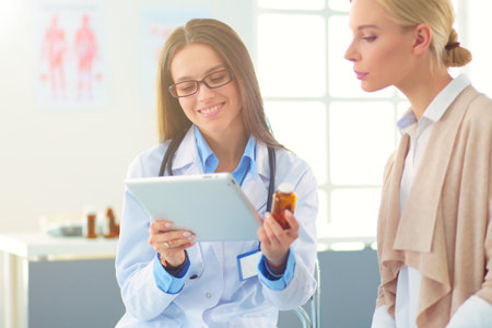 Doctor and patient discussing something while sitting at the table . Medicine and health care conceptの写真素材