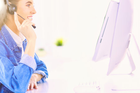 Portrait of beautiful business woman working at her desk with headset and laptopの写真素材