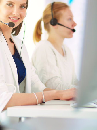 Smiling businesswoman or helpline operator with headset and computer at officeの写真素材