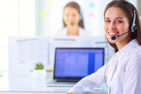 Smiling businesswoman or helpline operator with headset and computer at officeの写真素材