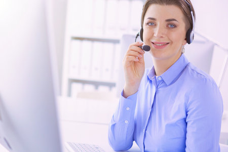 Serious pretty young woman working as support phone operator with headset in officeの写真素材