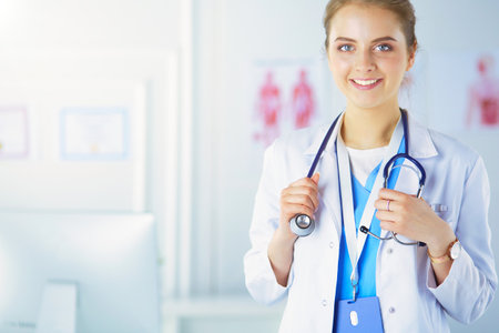Portrait of young woman doctor with white coat standing in hospitalの写真素材