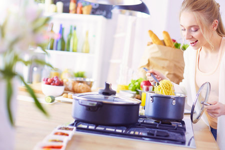 Beautiful young woman cooking in kitchen at homeの写真素材