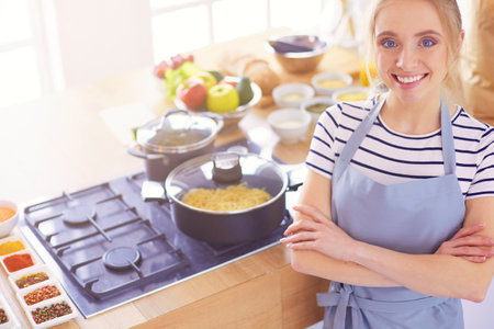 Young woman standing near desk in the kitchenの写真素材