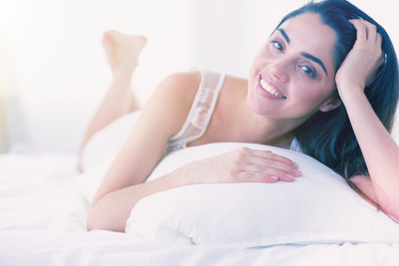 Pretty woman lying down on her bed at homeの写真素材