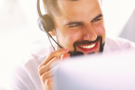 Portrait of a young man with a headset in front of a laptop computerの写真素材