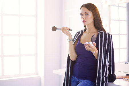 Closeup portrait of woman with makeup brush near faceの写真素材
