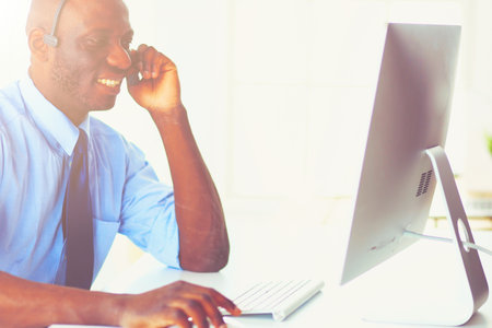 African american businessman on headset working on his laptopの写真素材