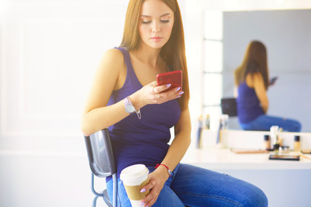 Young woman at cafe drinking coffee and talking on the mobile phoneの写真素材