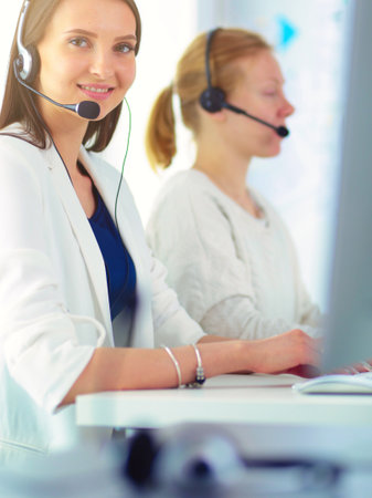 Smiling businesswoman or helpline operator with headset and computer at officeの写真素材