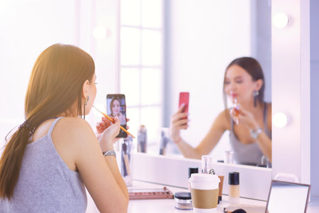 female young beautiful girl with curly hair and make-up. beautiful woman make self-portrait yourself by phoneの写真素材