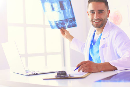 Handsome doctor is talking with young female patient and making notes while sitting in his office.の写真素材