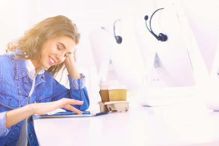 Smiling woman drinking coffee and using tablet in the cafeの写真素材