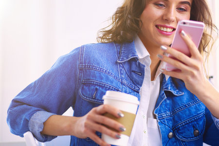 Young woman at cafe drinking coffee and talking on the mobile phoneの写真素材