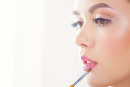 Beautiful girl with cosmetic powder brush for make up. Makeup. Make-up applying for perfect skinの写真素材