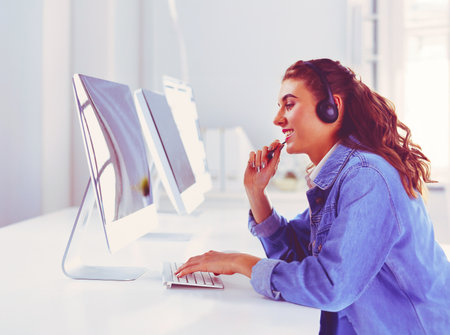 Smiling businesswoman with headset using laptop at the desk in workの写真素材