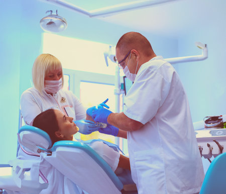 Young dentist and his assistant treating womanの写真素材