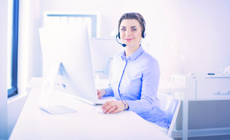 Serious pretty young woman working as support phone operator with headset in officeの写真素材