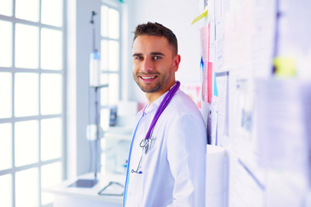 Young and confident male doctor portrait standing in medical office.の写真素材