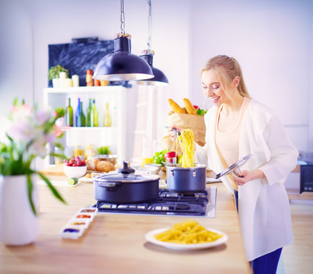 Beautiful young woman cooking in kitchen at homeの写真素材