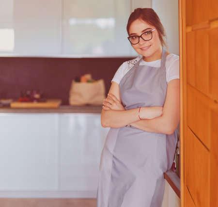 Young woman standing near desk in the kitchenの写真素材